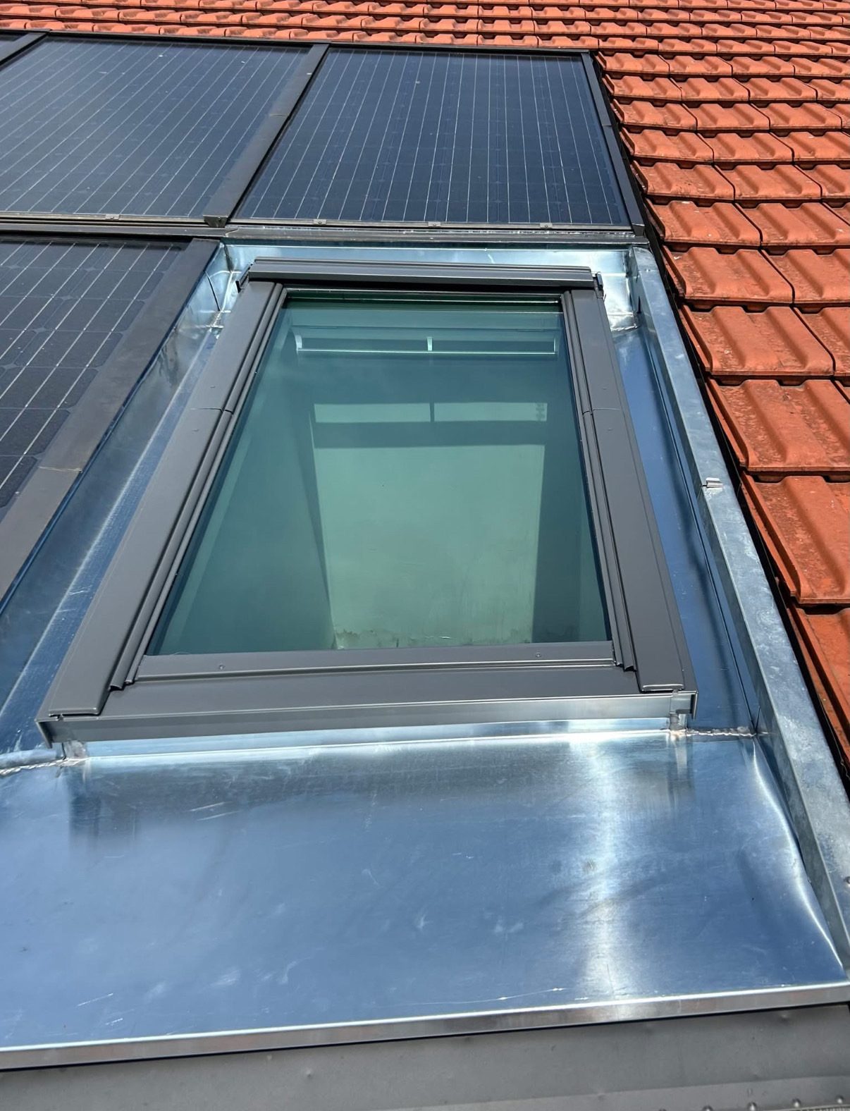 Fenêtre de toit habillée de zinc entre tuiles et panneaux